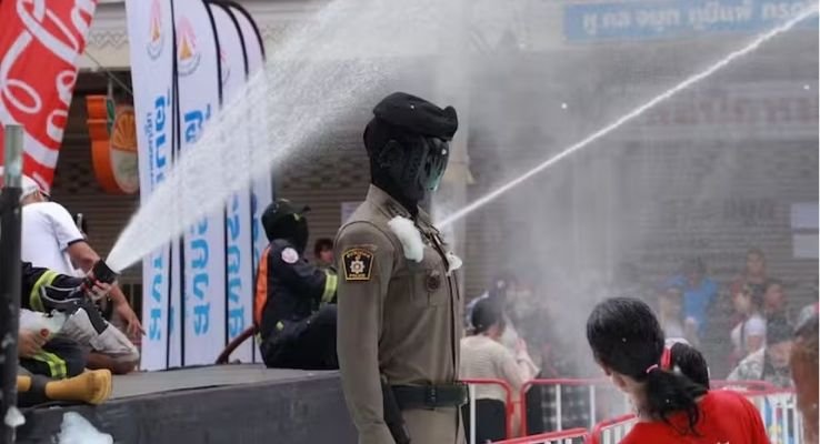 demonstração de robô policial com inteligência artificial sendo testado com jatos d'água em festival na Tailândia